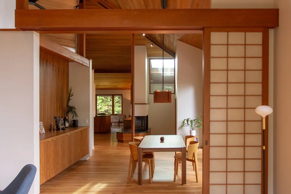 The dining room through the open shoji screen: cedar ceiling, clerestory windows, the table and the teak sideboard beyond.